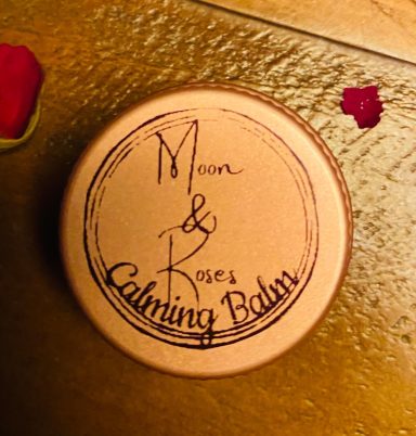 A small closed rose gold tin with Moon and Roses logo and calming balm written on the lid