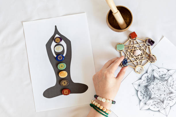 An outline of a body in meditation pose with chakra stones over each chakra, a candle and some crystals
