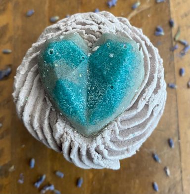 A big blue shiny heart melt topped on top of some grey bubble icing that has been piped so it ripples